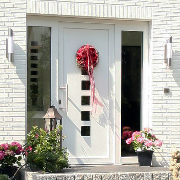 Usi-TAQ-VEKA-Softline-82-Ușă albă de PVC modernă de intrare cu decor festiv roșu și flori în fața casei.