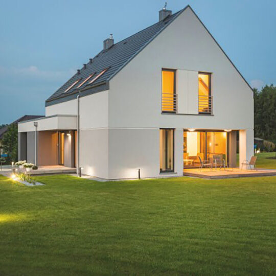 Fereastra-TAQ-VEKA-Softline-82-AD- Casă modernă cu acoperiș în două ape, fațadă albă și ferestre mari, iluminată ambiental, exemplu de arhitectură contemporană eficientă energetic.